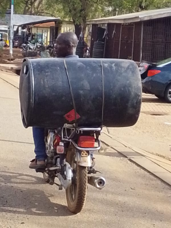 Motorcyclist transports large barrel through Tamale, Ghana