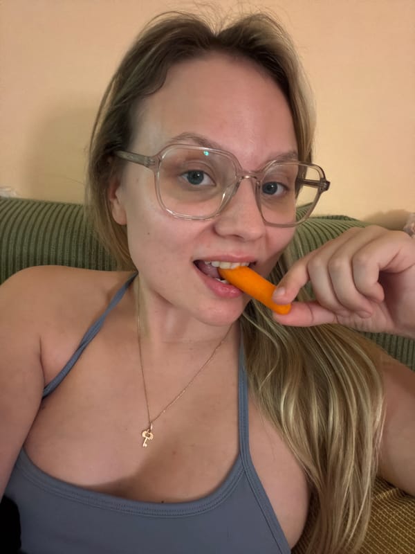 Woman eats carrot with dog companion in Tel-Aviv apartment
