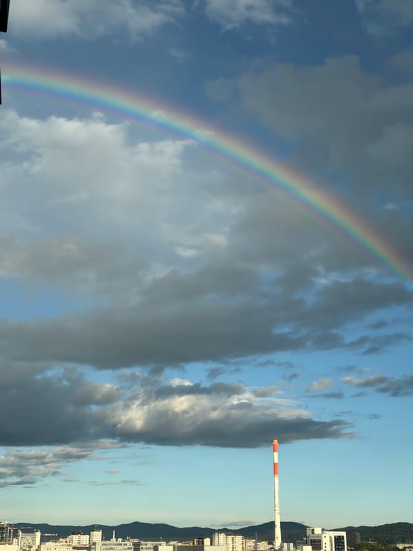 Rainbow appears over city near industrial smokestack