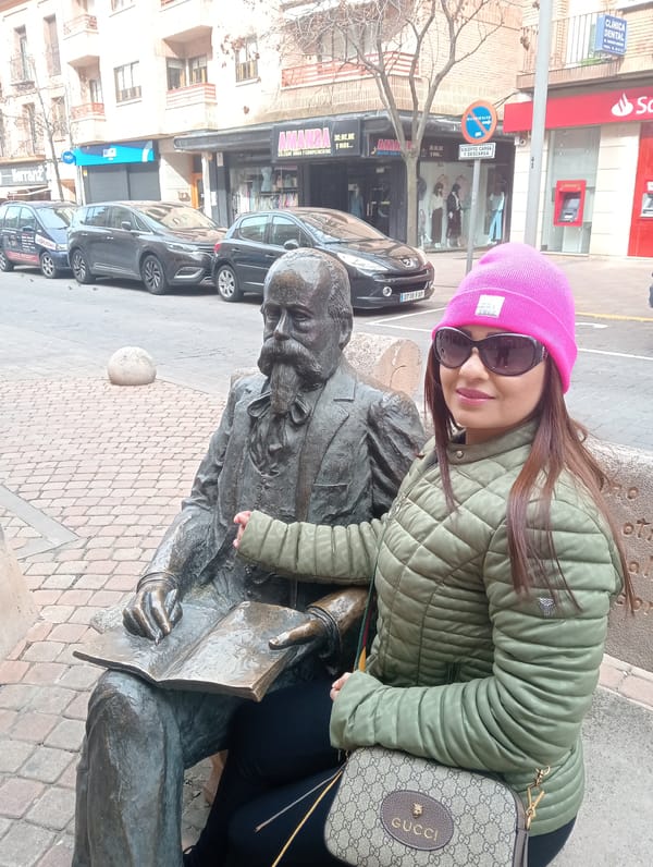 Tourist poses with bronze statue in Segovia streets