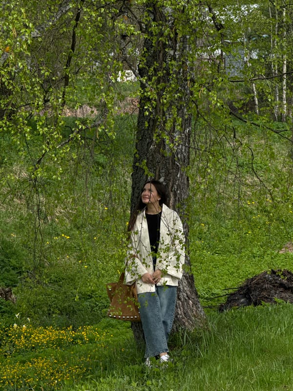 Woman rests against birch tree in Russian countryside