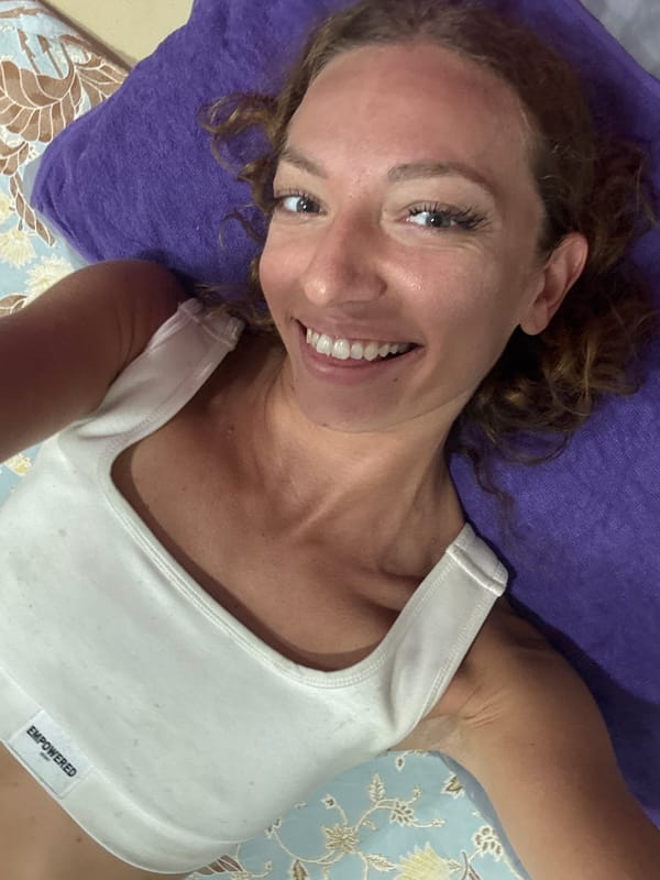 Woman in 'EMPOWERED' tank top photographed smiling in Thailand