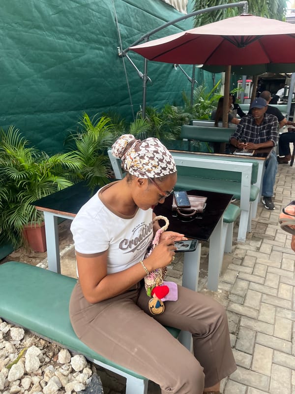 Woman uses smartphone at outdoor cafe in Karum, Nigeria