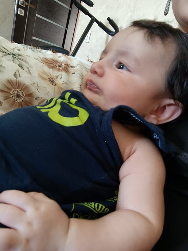 Baby in dark blue shirt gazes upward, Yerevan