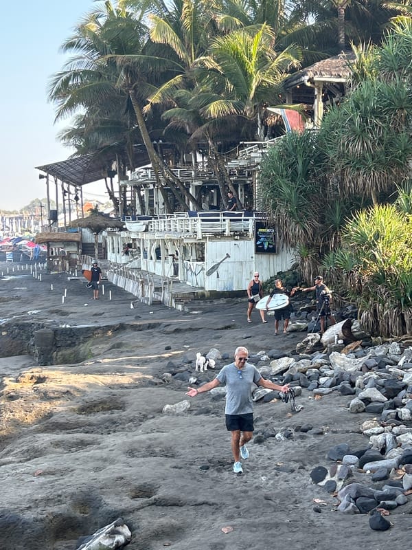 North Kuta black sand beach, surfers and beachgoers on a clear day