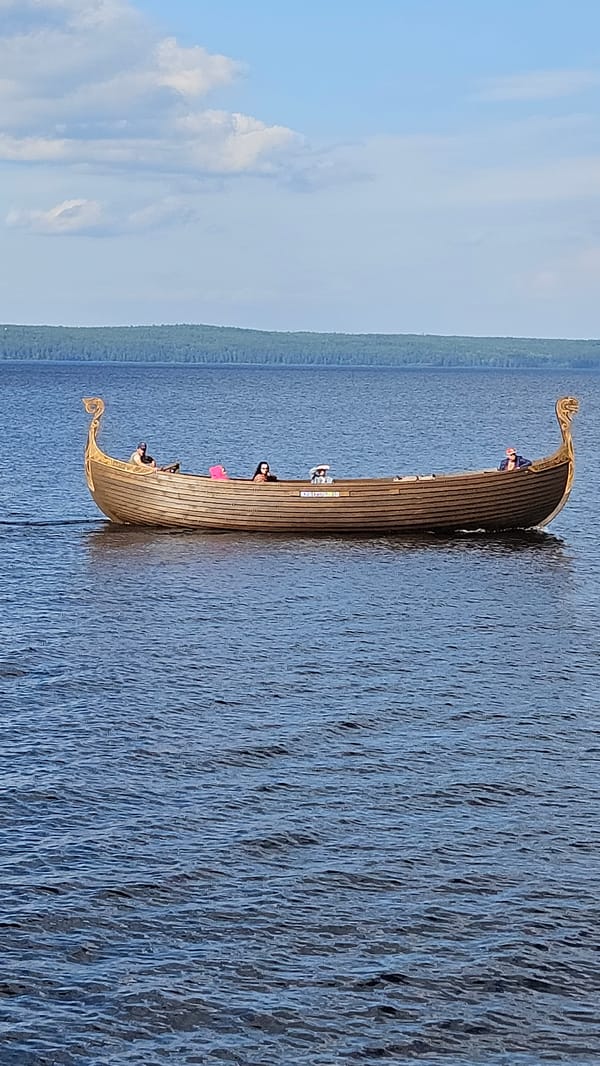 Sunny day at a waterfront park with Viking boats and kvas