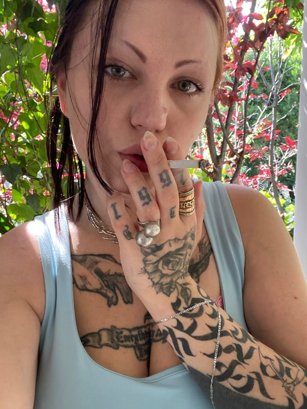 Tattooed woman smoking cigarette observed in Kunje, Montenegro