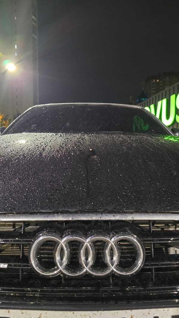 Rain-soaked luxury cars photographed in nighttime urban setting