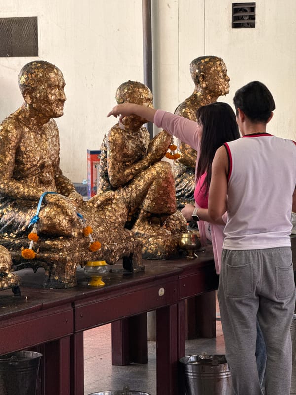 Devotees apply gold leaf to Buddhist statues in Bangkok temple