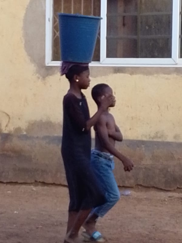 Children walk dirt path in Tamale, Ghana morning