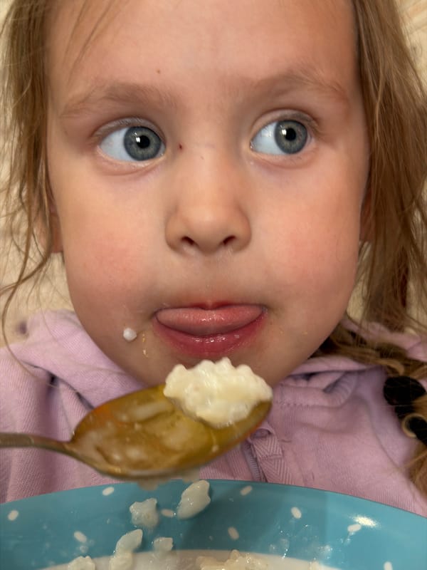 Young girl enjoys breakfast rice pudding in Chaikovsky, Russia