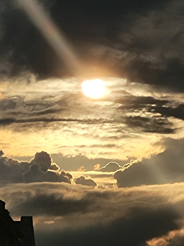 Sun breaks through dramatic clouds over a residential street at sunset