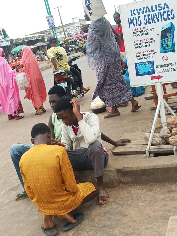 Three people sitting on a curb at an urban marketplace