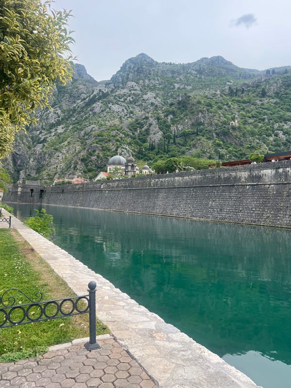 Visitor documents historic Kotor waterfront and stone fortifications