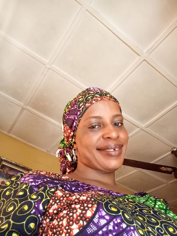 Woman in colorful headscarf photographed smiling indoors in Narayi