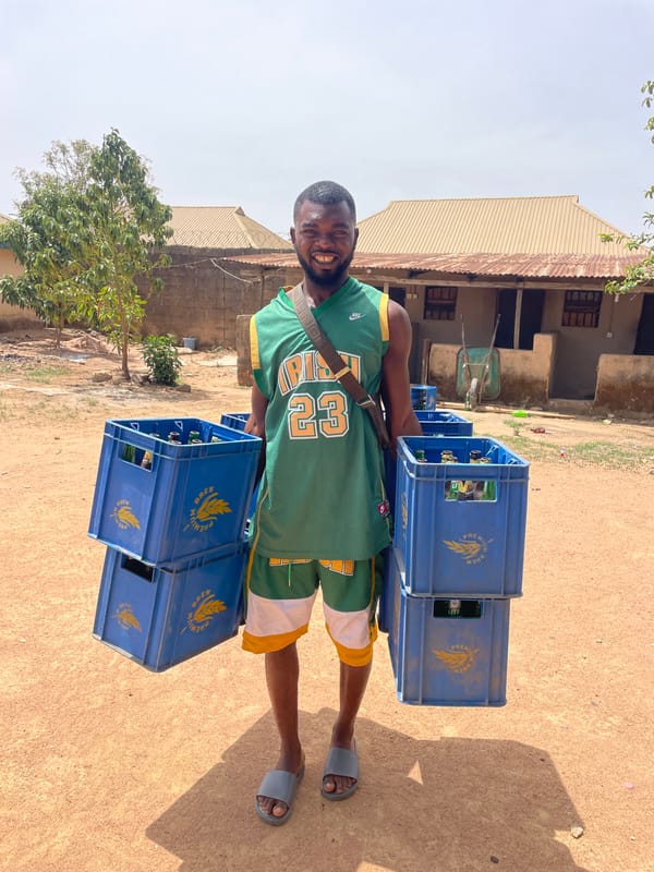 Man carries plastic crates in sunny Barakin Akawo