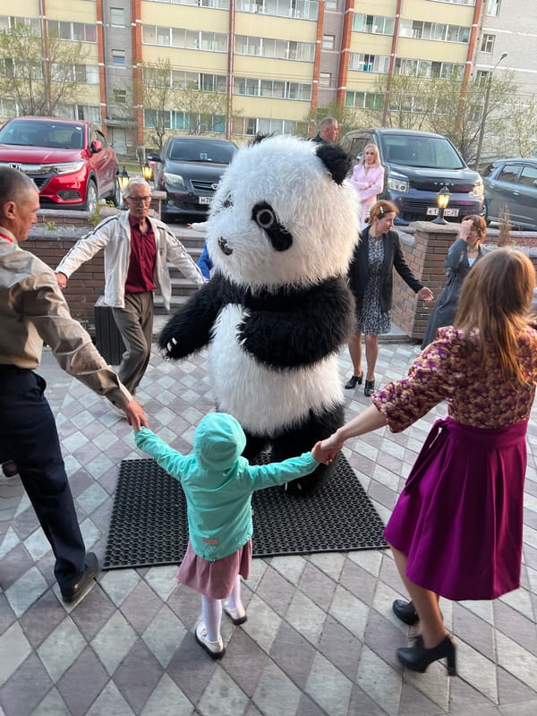 Community gathers for panda costume celebration outside apartment building