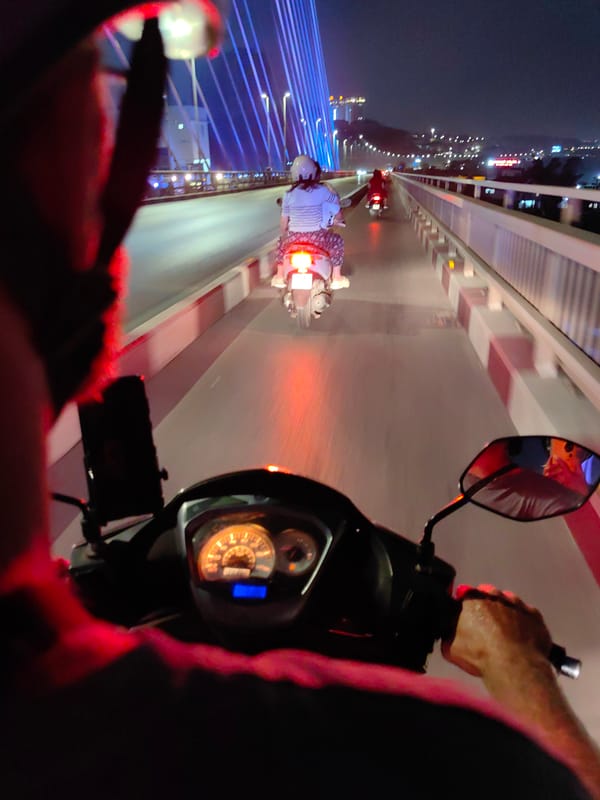 Motorcycles cross bridge at night in Hong Gai Ward