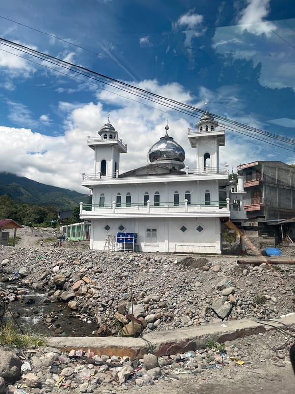 White mosque with twin minarets overlooks rocky stream in Simpanglayang
