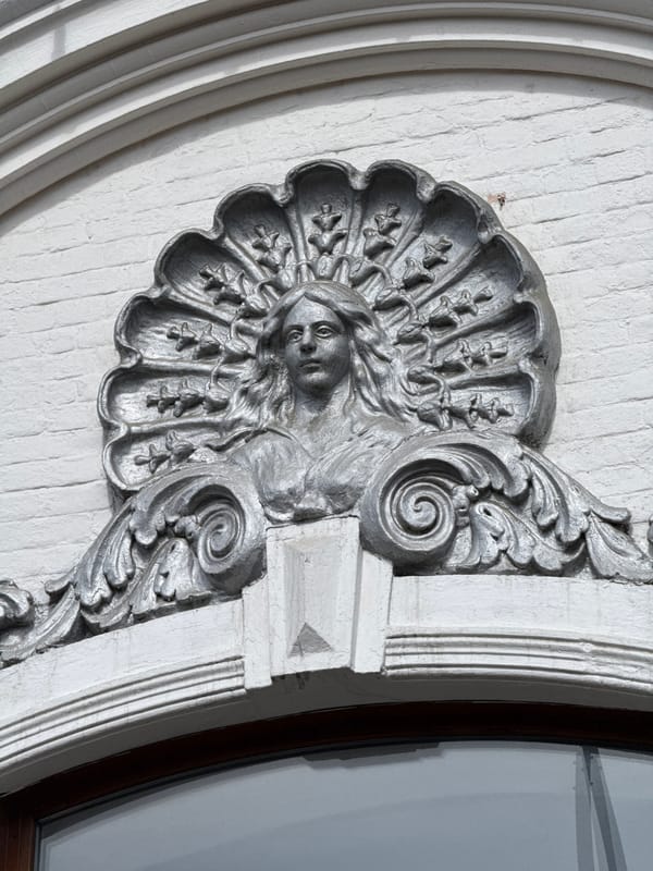 Ornate facial motif spotted on white brick architecture