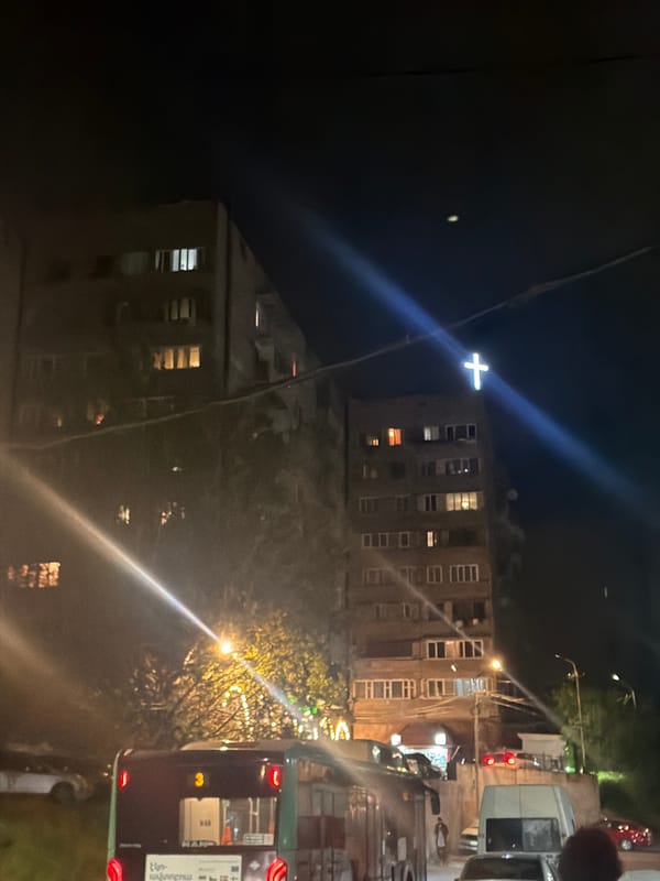 Illuminated cross atop building observed in nighttime Yerevan