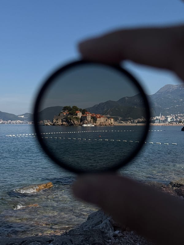 Sveti Stefan's stone islet framed from the shore, sunny morning