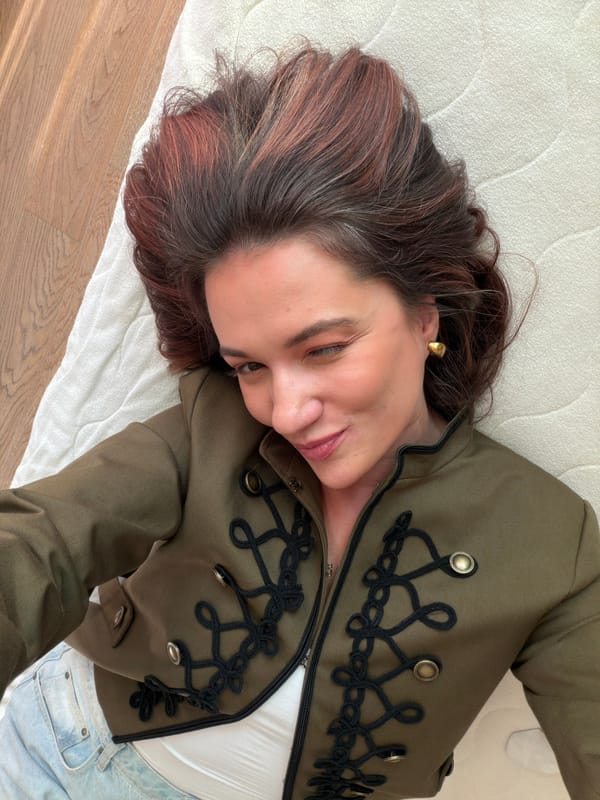 Woman in military jacket rests on bed in Belgrade