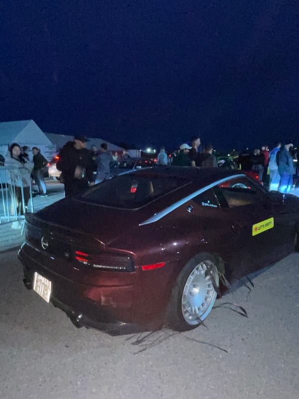 Nighttime drift event: track action, crowd, and car damage