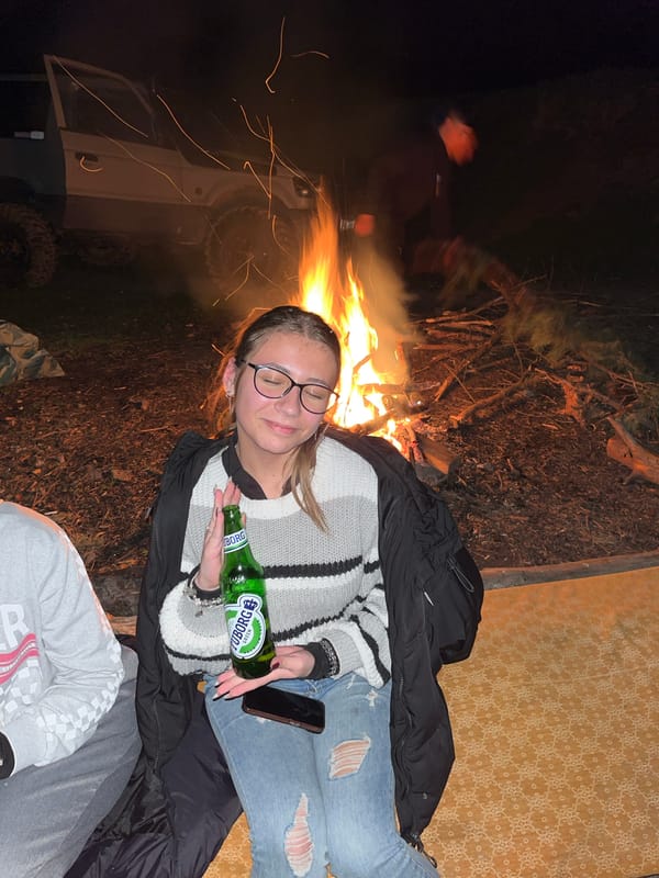 Woman enjoys evening campfire with beer in Karavelovo, Bulgaria