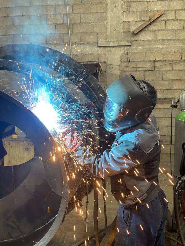 Welder fabricates curved metal structure in Montenegro workshop