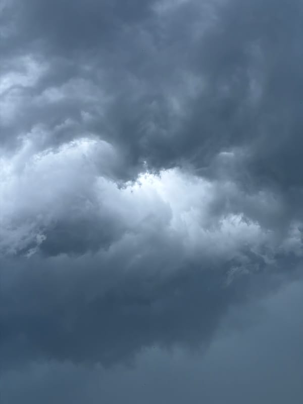 Dark storm clouds gather over a rooftop in an unknown city