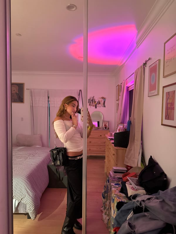 Mirror selfie in LA bedroom, white top and black boots