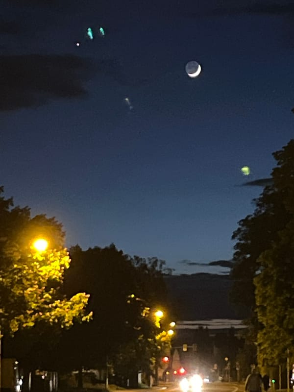 Crescent moon and bright celestial object observed in urban sky
