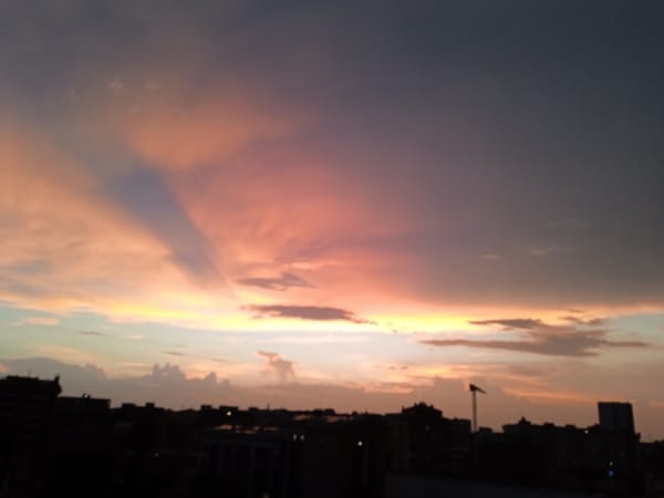 City skyline silhouetted against a vivid summer sunset