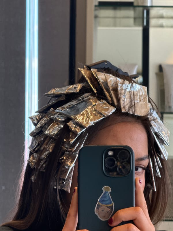 Salon client takes selfie during hair highlighting treatment