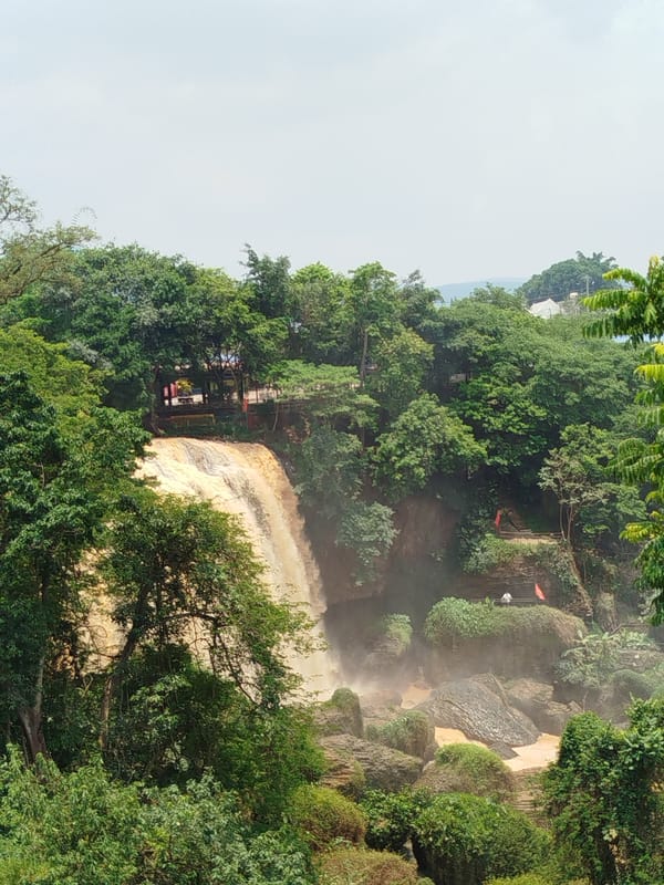 Tourist documents Vietnamese waterfalls and religious statues during morning visit