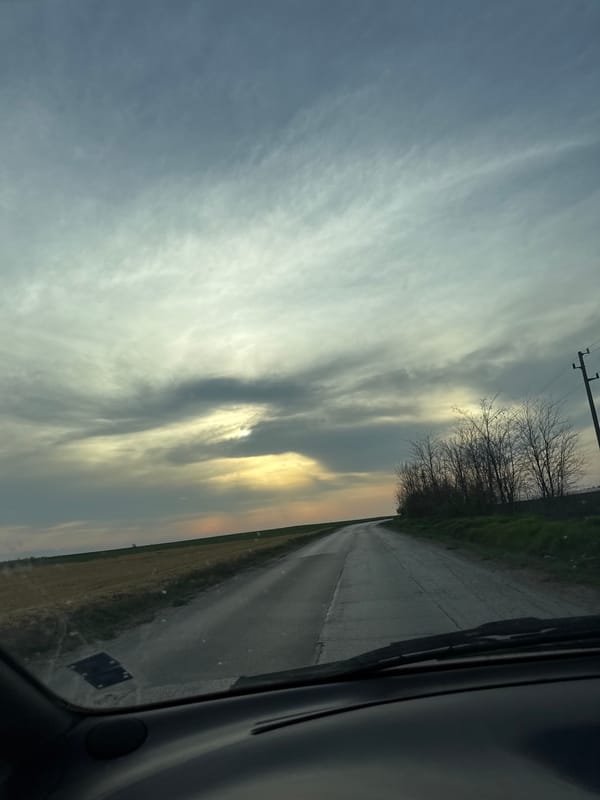 Motorist drives wet road through Bulgarian countryside fields