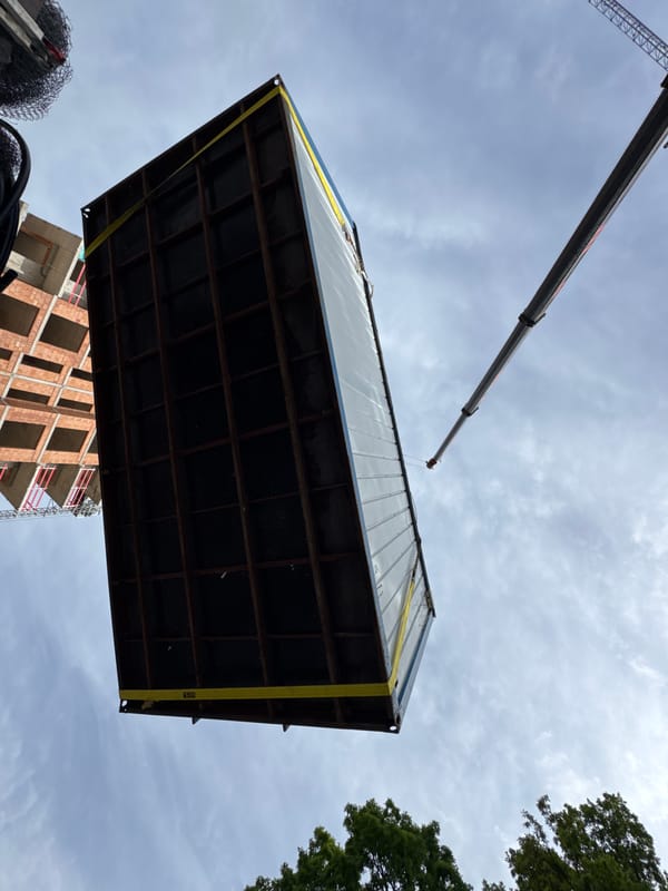 Crane lifts container at construction site during morning hours