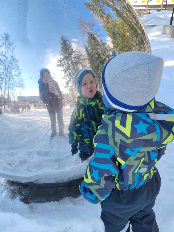 Child plays near reflective art in snowy Russian park