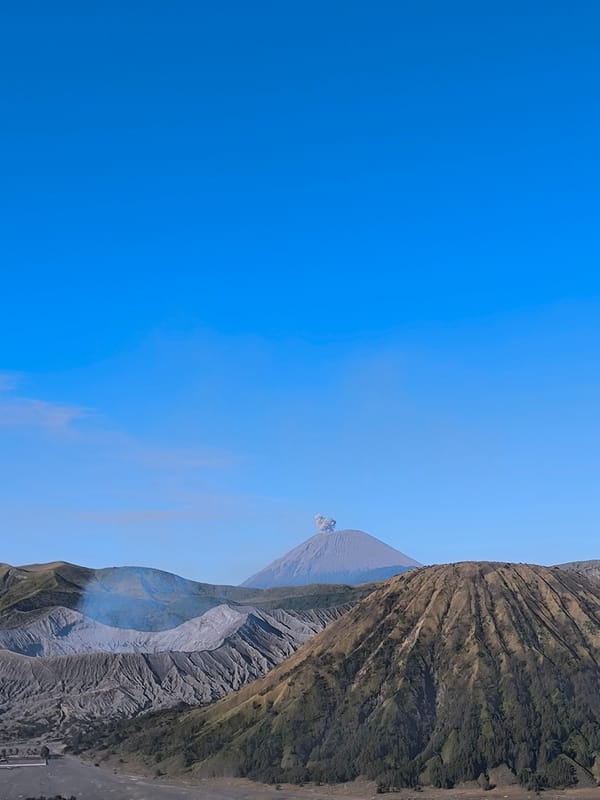 Cone volcano rises under clear skies in lush volcanic landscape