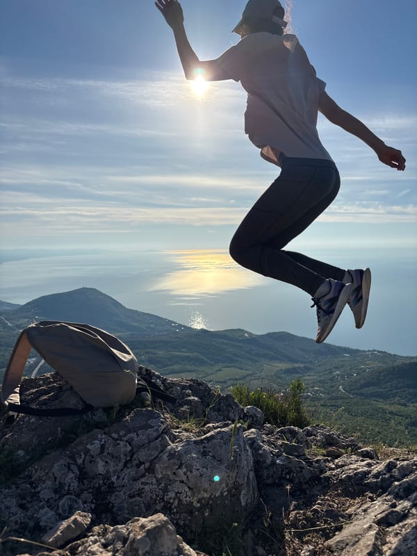 Person captured jumping on mountain peak overlooking coast