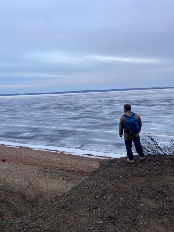 Man observes frozen waterway from embankment in Noviy, Russia