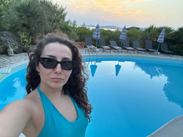 Dusk at an Alghero poolside, coastal hills in the background