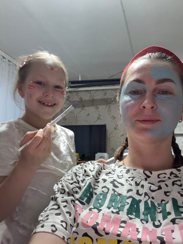 Child applies blue face paint to woman in Russian home