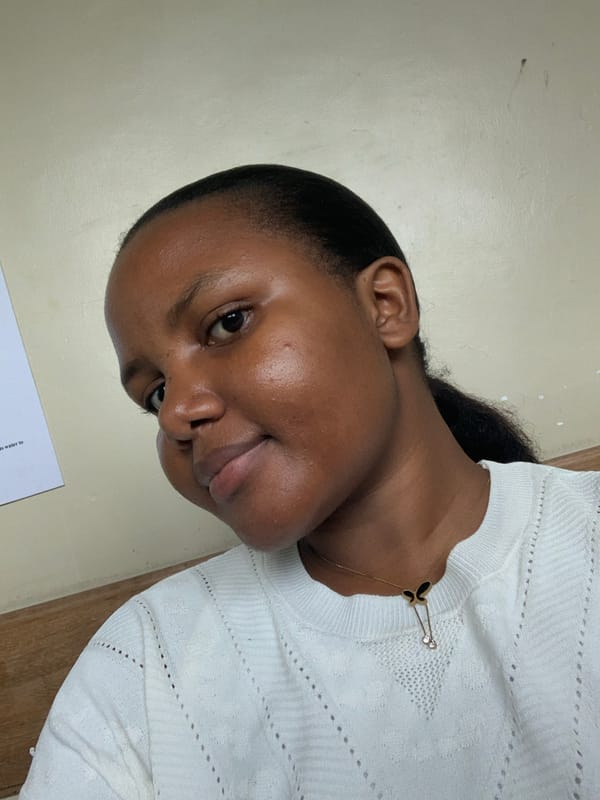Woman photographed indoors in Dar es Salaam wearing butterfly necklace