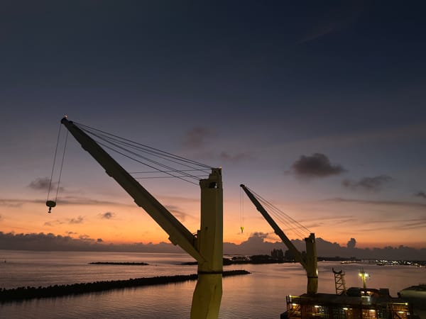 Industrial cranes captured against colorful sky at waterfront location