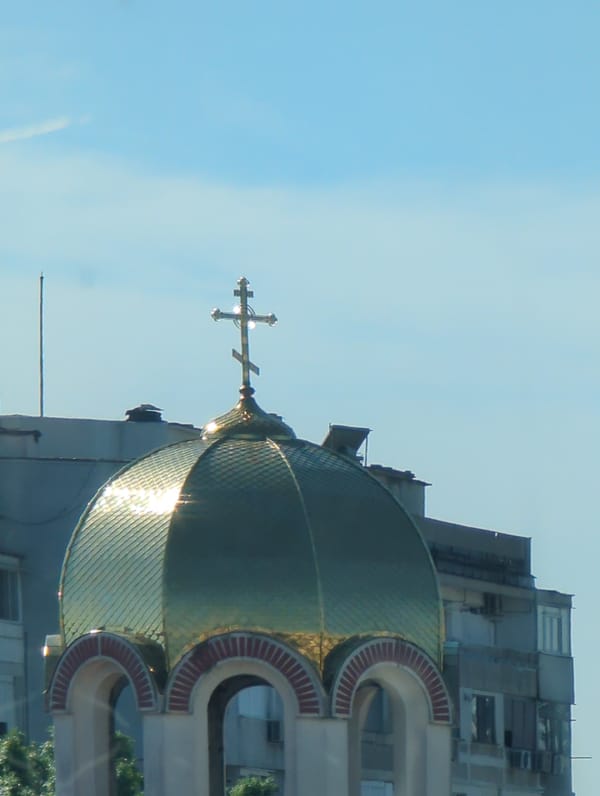 Cat naps by a curtain, golden dome gleams in the sun