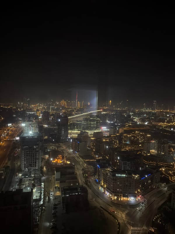 Dubai at night from above — skyline, waterways, and highways.