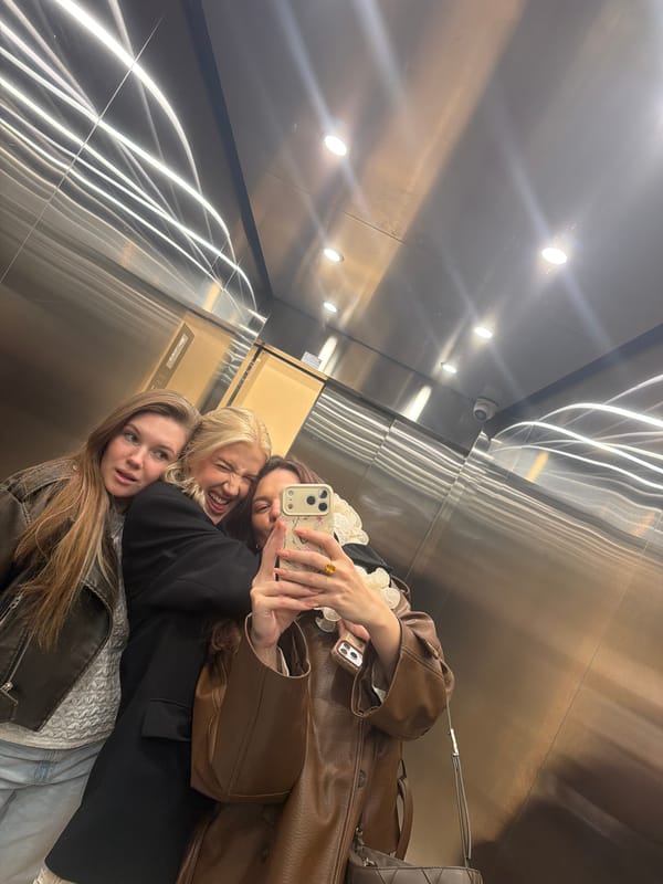 Three women take selfie in stainless steel elevator