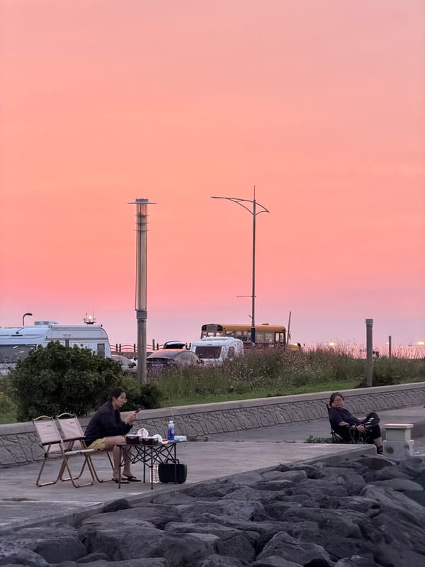 Dusk along Jeju's volcanic coastline, grill lit, sky glowing